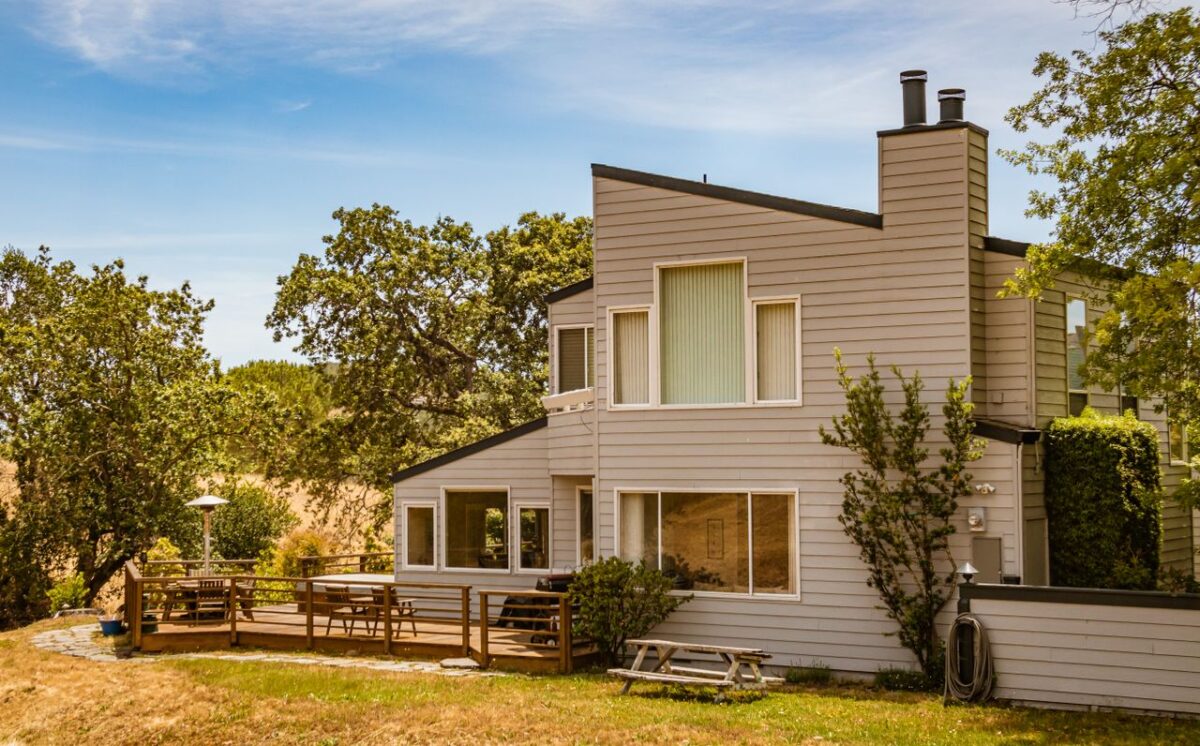 services-bg Contemporary suburban house featuring large glass windows and a spacious deck in a lush outdoor setting.