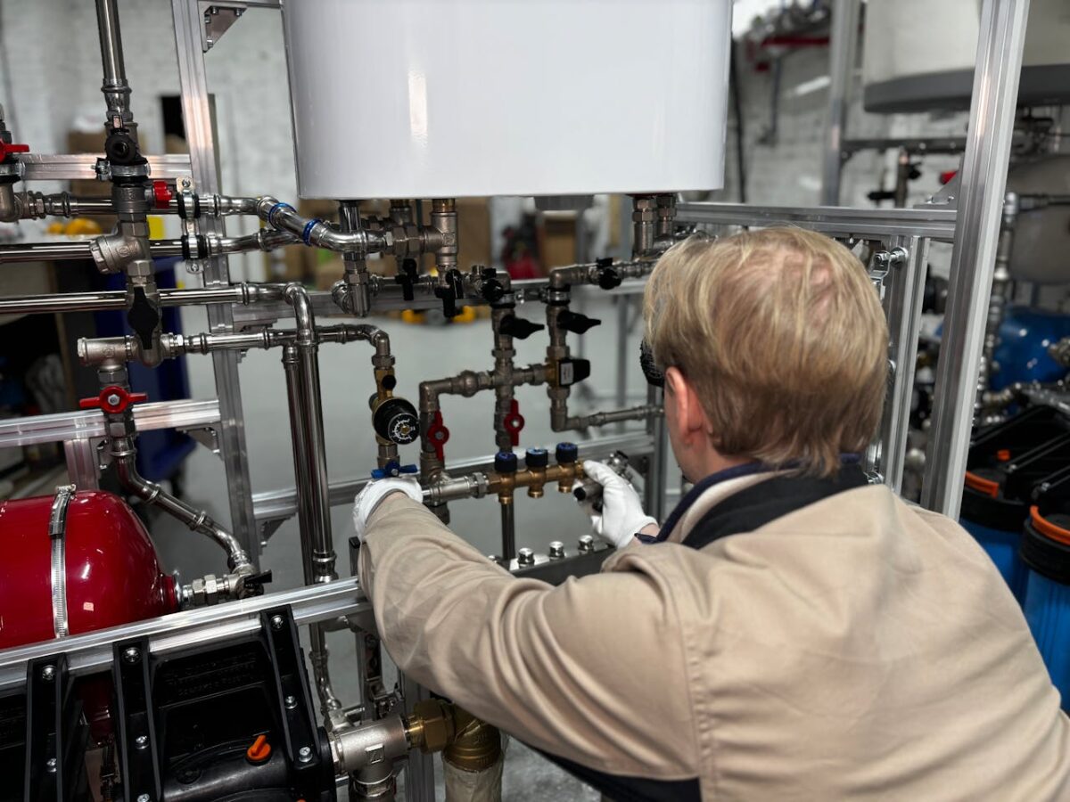 Engineer working on industrial pipe system in a factory for heating and production adjustment.